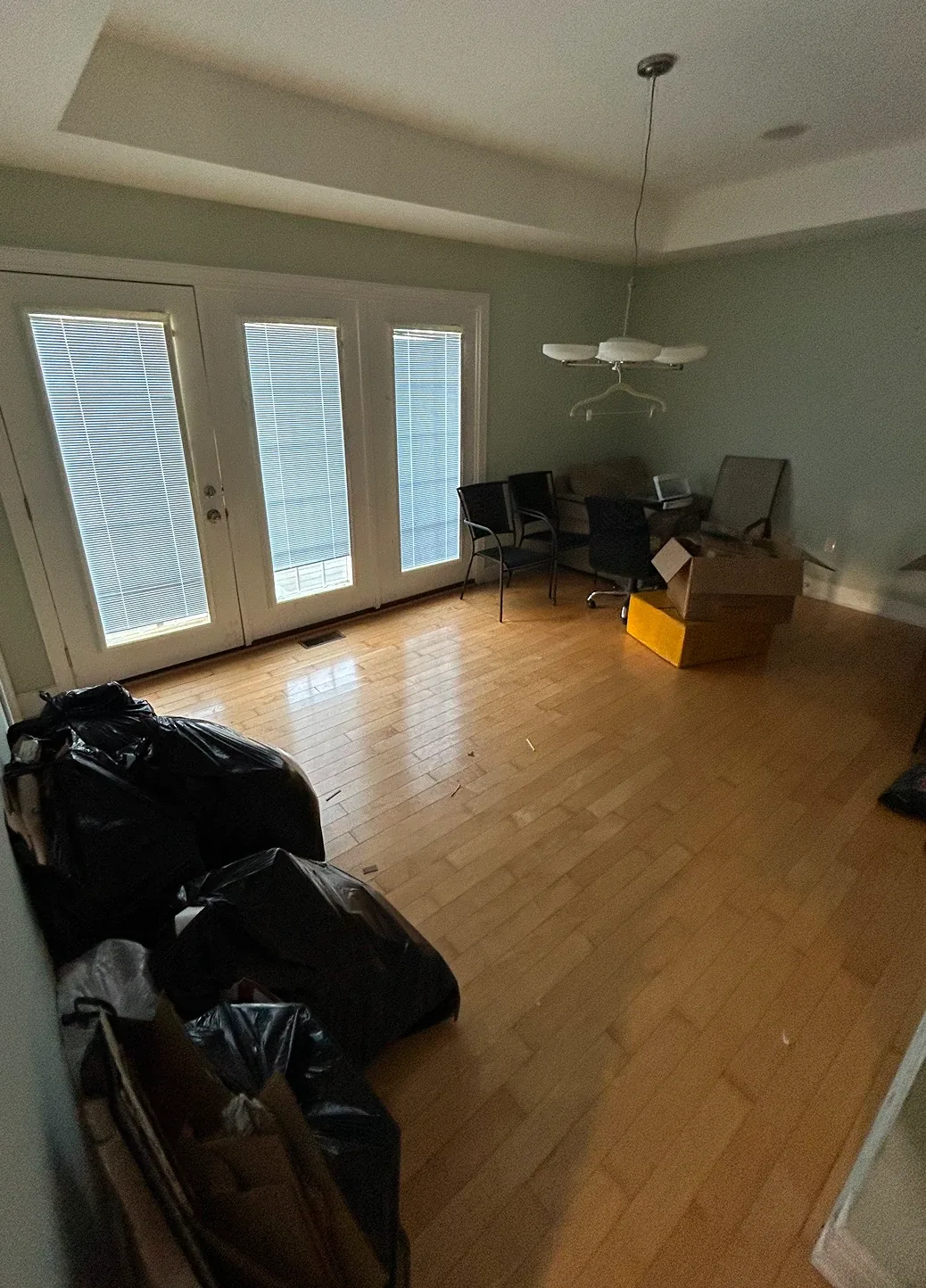Empty room interior featuring polished hardwood floors and large glass doors leading outside.