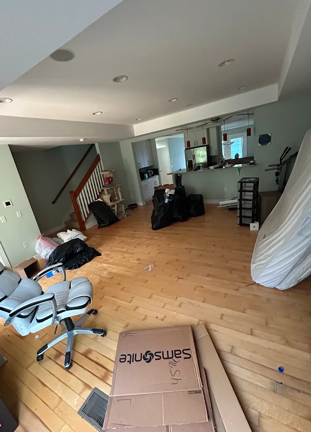 Interior shot of a room undergoing renovation or moving, with open floor space and items piled in the corner.